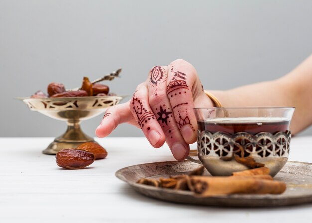 Free Photo person with mehndi holding tea cup on table