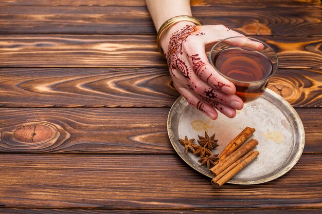 Person with mehndi holding tea cup on table