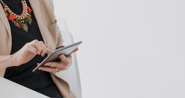 Person with necklace holding a tablet with copyspace