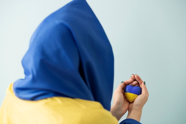 Person with ukrainian flag holding stone painted in blue and yellow