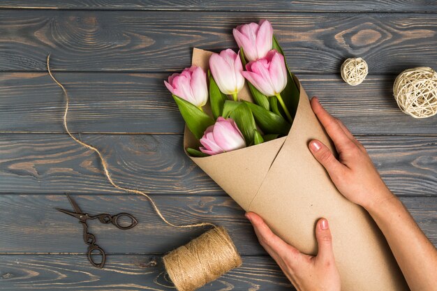 Person wrapping bright tulips in pack paper