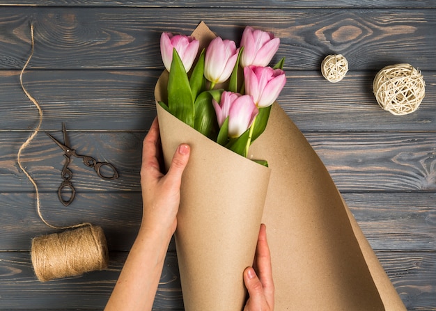 Person wrapping pink tulips in pack paper