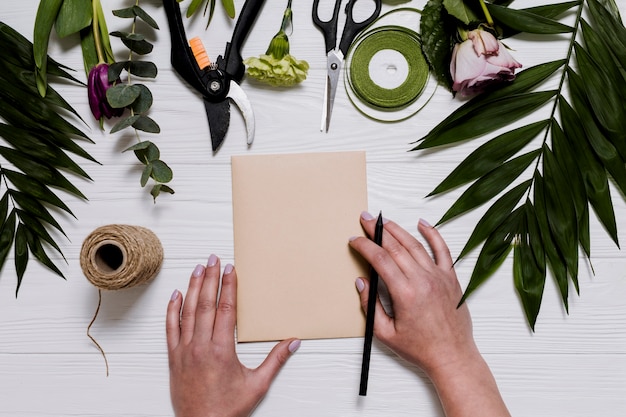 Free Photo person writing on florist table