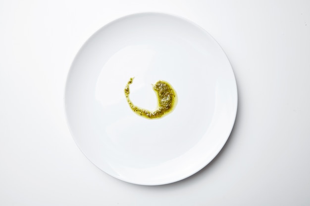 Free photo pesto sause on white blank plate isolated top view