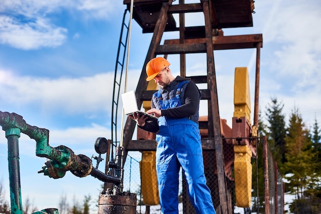 Free Photo petroleum engineer using laptop in oil field