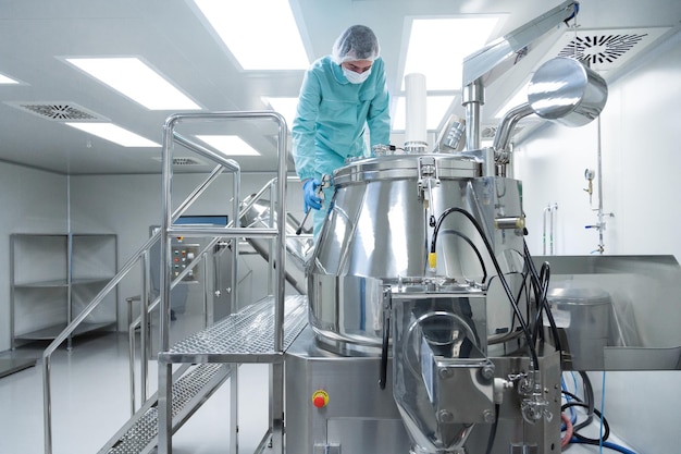 Pharmaceutical factory man worker in protective clothing operate production line in sterile working conditions