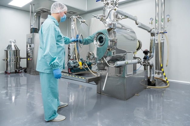 Free photo pharmaceutical factory man worker in protective clothing working on equipment in sterile working conditions