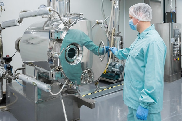 Pharmaceutical factory man worker in protective clothing working on equipment in sterile working conditions