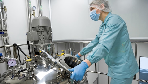 Free photo pharmaceutical factory woman worker in protective clothing operating production line in sterile environment