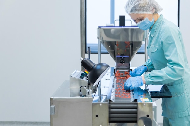 Free photo pharmacy industry woman worker in protective clothing operating production of tablets in sterile working conditions