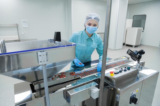 Free photo pharmacy industry woman worker in protective clothing operating production of tablets in sterile working conditions