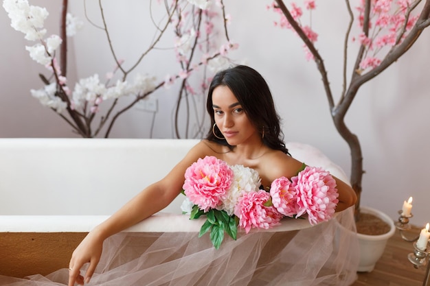 Photo of adorable girl holding bunch of colorful flowers and sittin in a bathtub High quality photo