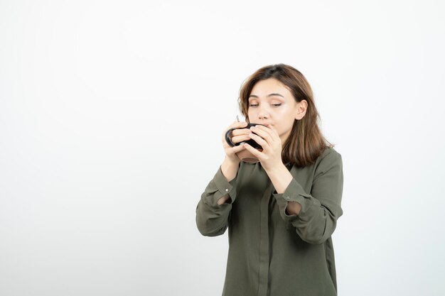 Photo of adorable young girl drinking cup of hot coffee. High quality photo