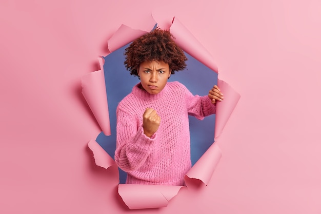 Free photo photo of annoyed dark skinned woman with afro hair clenches fist demonstrates anger