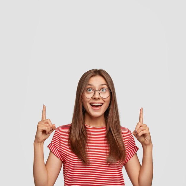 Photo of attractive dark haired young European woman discusses amazing copy space upwards