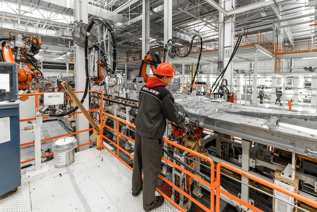 Free photo photo of automobile production line welding car body modern car assembly plant auto industry male worker in an orange protective helmet