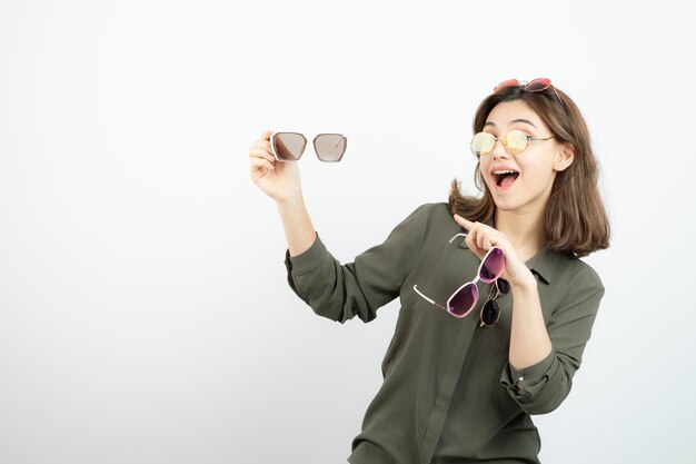 Photo of beautiful woman holding colorful sunglasses over white. High quality photo