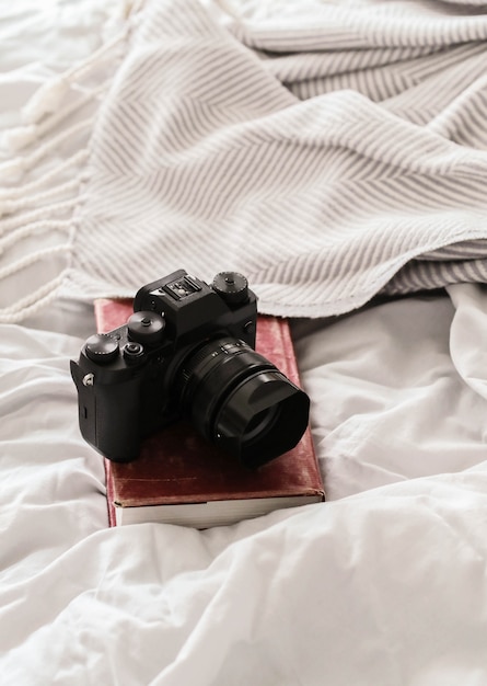 Free photo photo camera on top of a book on a bed