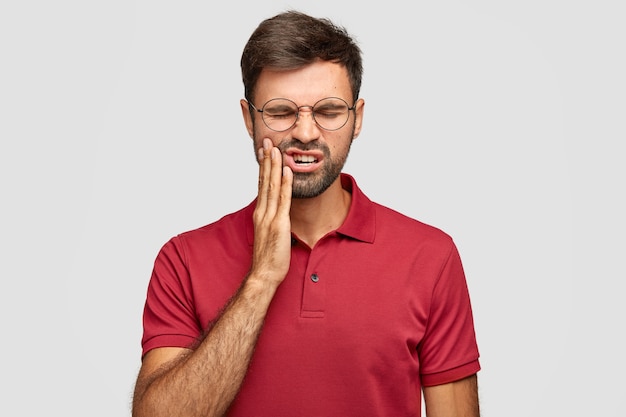 Free photo photo of caucasian man suffers painful toothache, has rotten tooth, needs to visit dentist