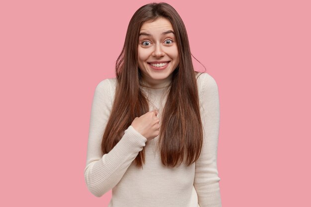 Photo of cheerful brunette lady points at herself, has toothy smile, asks about something, being chosen