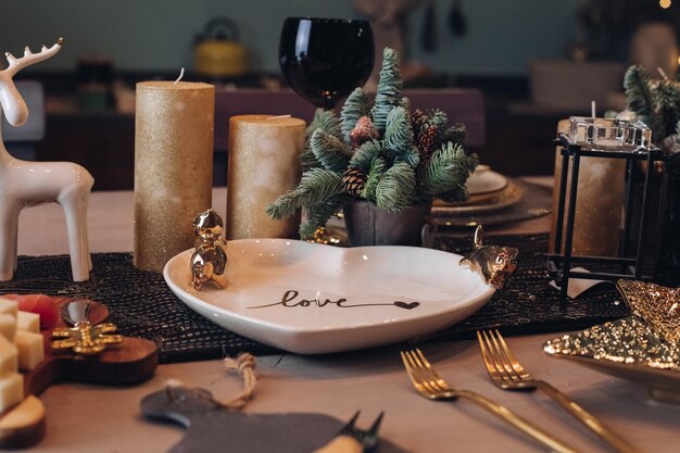 Photo of Christmas table decoration with festive dinnerware with candles. New Year eve concept