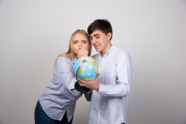 Photo of cute couple standing and holding earth globe