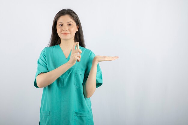 Photo of female doctor with a spray over white. 