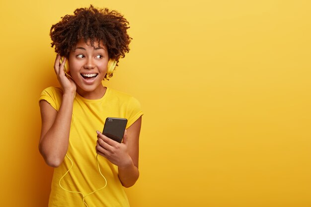 Photo of female meloman listens favourite playlist in headphones