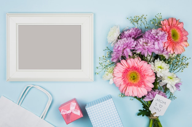 Free photo photo frame near bouquet of fresh flowers with title on tag near packet, present and notebook