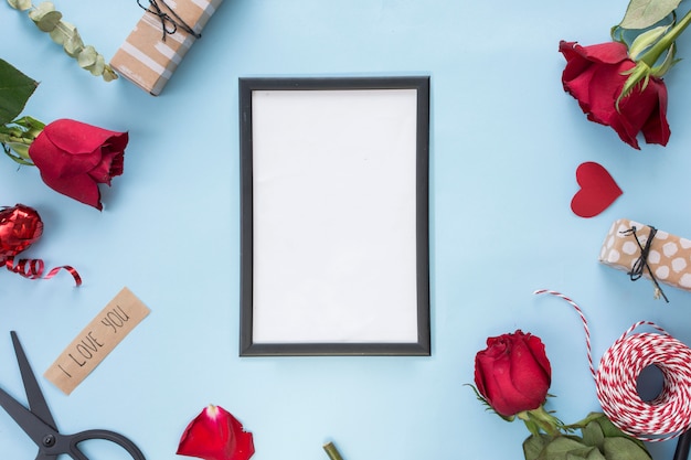 Photo frame near scissors, roses and bobbin of twists