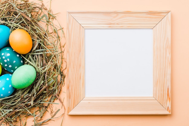 Free photo photo frame near set of bright easter eggs in nest