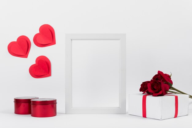 Photo frame between present with flowers, paper hearts and boxes