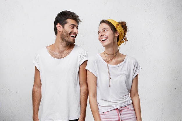 Photo of handsome man with dark hair and cute female looking at each other with wide smiles being cheerful to meet.