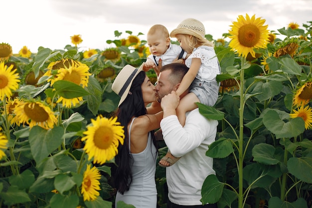 Photo of happy family. Parents and daughter. Family together in sunflower field. Man in a white shirt.