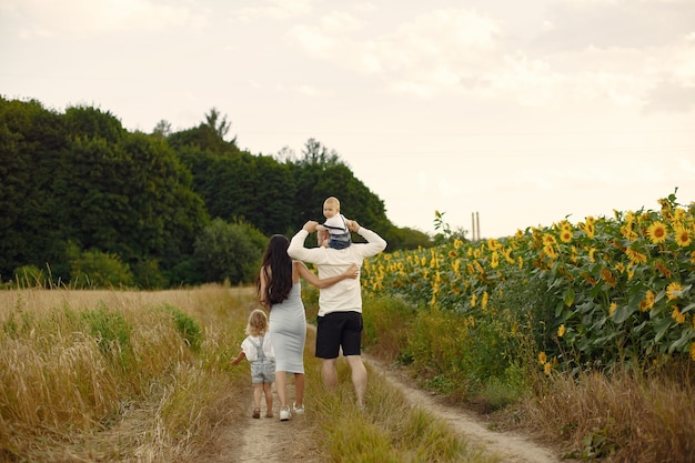 Photo of happy family. Parents and daughter. Family together in sunflower field. Man in a white shirt.