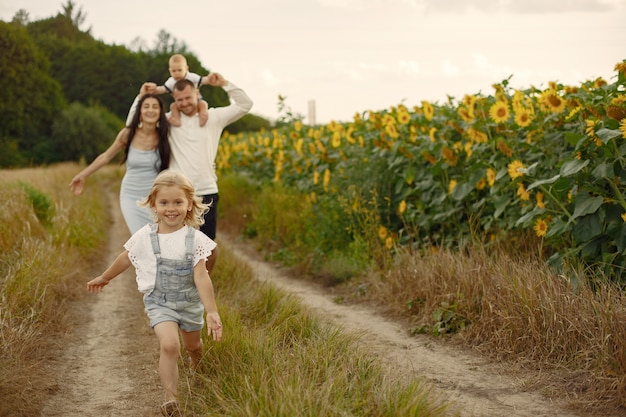 Photo of happy family. Parents and daughter. Family together in sunflower field. Man in a white shirt.