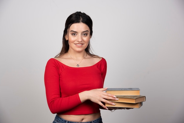 Photo of a lovely woman holding a stack of books .