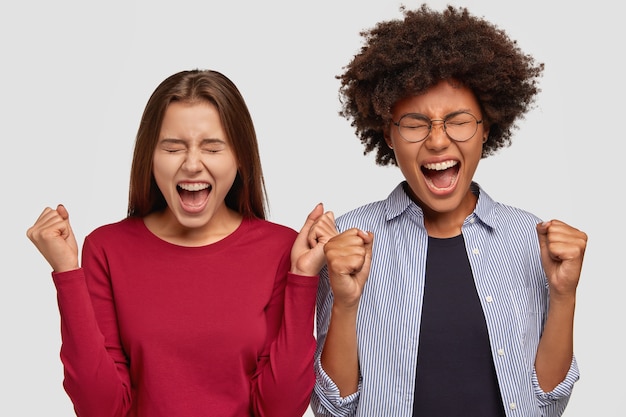 Free photo photo of overjoyed mixed race women raise clenched fists