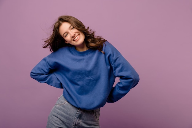 Free photo photo of pretty fairskinned young girl looking at camera with smile on her face in purple background stylish woman having a good time