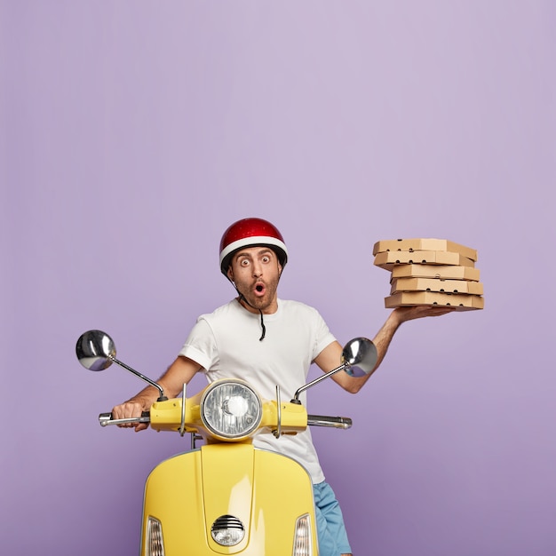 Free photo photo of scared deliveryman driving yellow scooter while holding pizza boxes