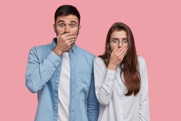 Free Photo photo of scared speechless lady and man cover mouthes with palms, have stupefied expressions, dressed in elegant shirt