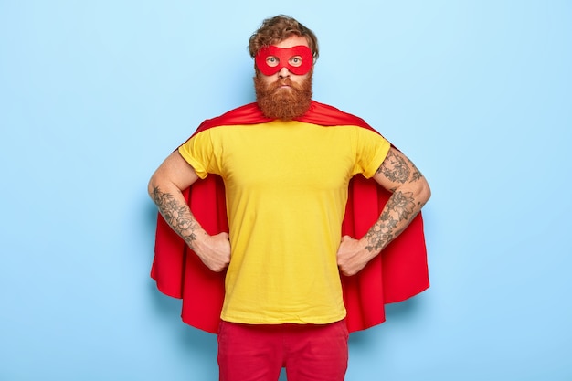 Photo of serious male in superhero costume, keeps hands on waist, possesses extraordinary talents