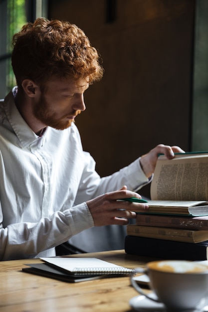 Free Photo photo of serious redhead bearded student, preparing for exam in a cafe