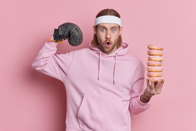 Free Photo photo of shocked unshaven man trains in boxing gloves