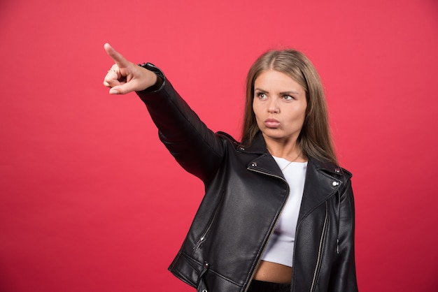 Photo of woman in leather jacket pointing away and giving direction