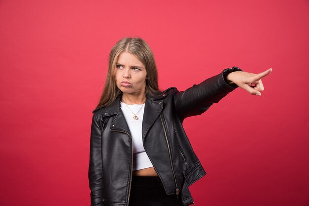 Photo of woman in leather jacket pointing away and giving direction