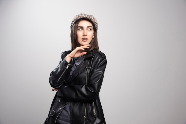 Photo of a woman looking away in black leather jacket and cap.