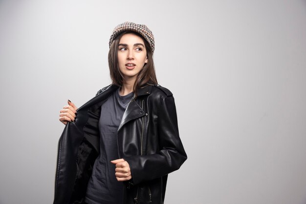 Photo of a woman looking away in black leather jacket and cap.