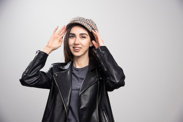 Photo of a woman posing in black leather jacket and cap.