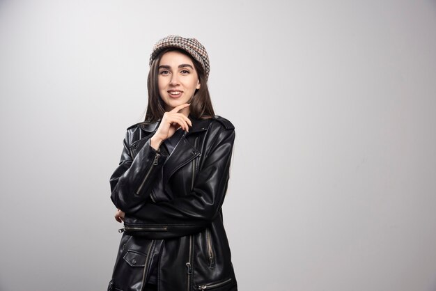 Photo of a woman posing in black leather jacket and cap.